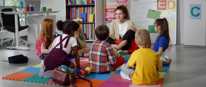 Woman and nursery school children sitting on the floor