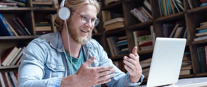 Man with headphones on laptop in library