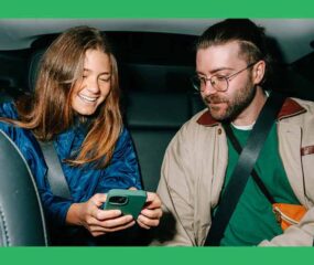 two people in the back of a car looking at a phone