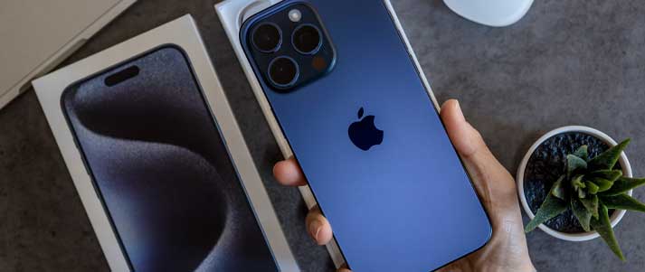 A person holding an iPhone 15 pro max in the colour blue titanium